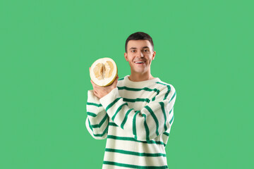 Young man with half of pomelo on green background