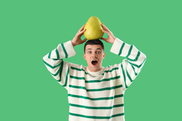 Shocked young man with pomelo on green background