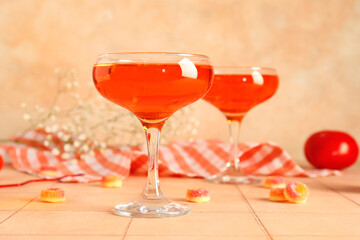 Glasses of tasty cocktail with marmalade on beige tile table, closeup. Valentine's Day celebration
