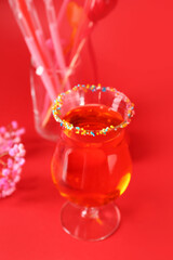 Glass of tasty cocktail on red background, closeup. Valentine's Day celebration