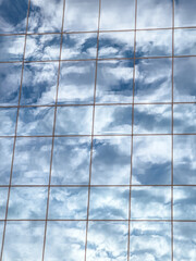 cloudy sky reflected in glass facade of modern office building. urban architectural background.