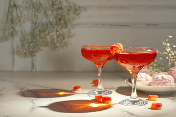 Glasses of tasty cocktail with sweets on light table, closeup. Valentine's Day celebration