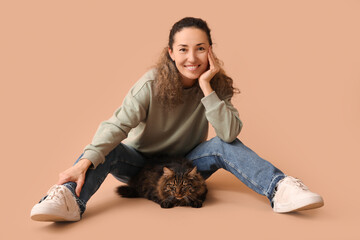 Mature woman with cute cat sitting on brown background - obrazy, fototapety, plakaty