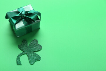 Paper clover with gift box on green background. St. Patrick's Day celebration