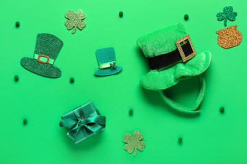 Paper clovers with leprechaun's hats and gift box on green background. St. Patrick's Day celebration