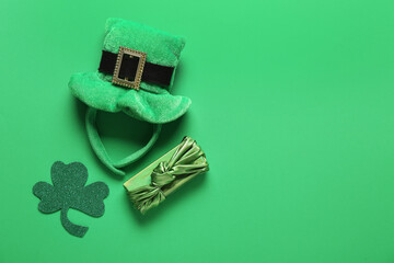 Gift box with leprechaun hat and paper clover on green background. St. Patrick's Day celebration