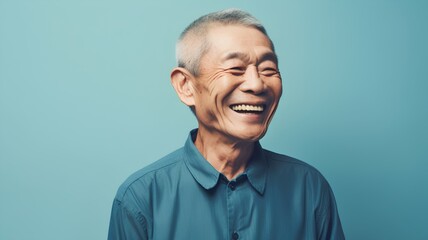 Portrait of a happy senior asian man laughing on blue background