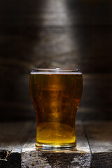 Glass of pale lager beer rustic wooden setting backlit spotlight mood lighting copy space 