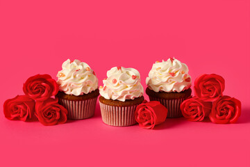 Tasty cupcakes with rose flowers for Valentine's Day on pink background