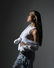 close up portrait of brunette female asian model wearing casual clothes, double denim jean outfit. Isolated on dark studio background with shadows. strong fashion model posing.