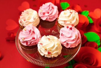 Stand with tasty cupcakes and paper rose flowers for Valentine's Day on red background