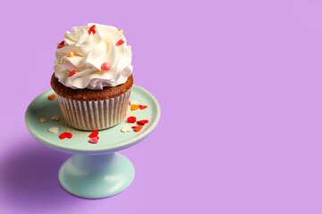 Stand with tasty cupcake for Valentine's Day on purple background
