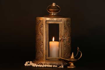 Muslim lantern with burning candle, Aladdin lamp and prayer beads for Ramadan on dark background