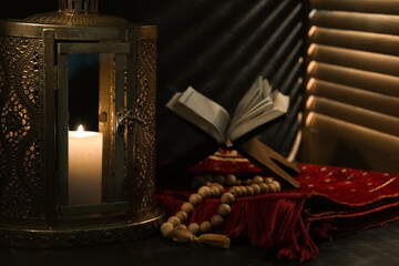 Muslim lantern, prayer beads and Koran for Ramadan on table against dark background