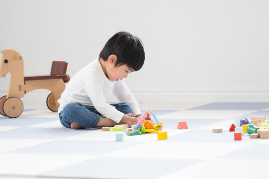 Toddler playing with building blocks Image of a room in a nursery school, kindergarten, or home