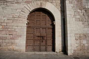 Fototapeta na wymiar Old paneled weathered wooden door in stone wall on street