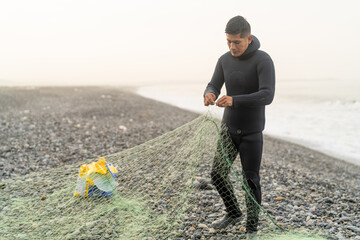 Man wearing wetsuit preparing a net to fish