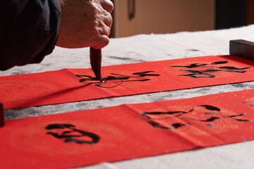 An old calligrapher writes couplets during the Chinese Year of the Dragon.
Translation: The...