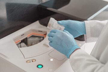 Close up of scientist's hand in gloves putting a small plastic test tube in a microcentrifuge