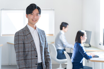 オフィスにいるカメラ目線のジャケットを着た若い日本人男性