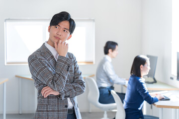 オフィスで考えるジャケットを着た若い日本人男性