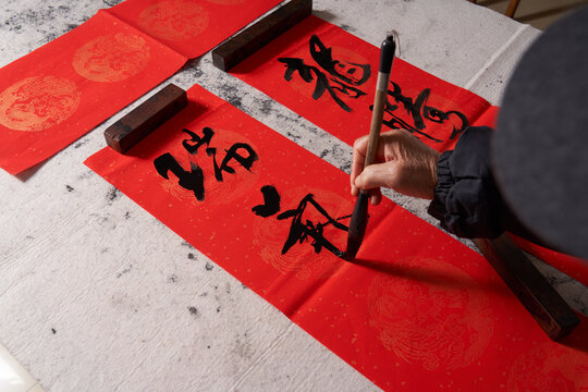 An old calligrapher writes couplets during the Chinese Year of the Dragon.
Translation: The auspicious energy brings auspiciousness and the wealth is abundant.
