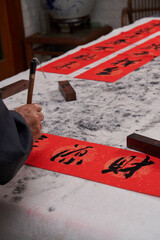 An old calligrapher writes couplets during the Chinese Year of the Dragon.
Translation: The...