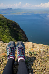 tourist legs in trekking shoes, sea view from a cliff