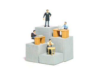 Miniature tiny people toy figure photography. Organization hierarchy and work monitoring illustration concept. A businessman and businesswoman working on different level at tower building