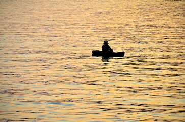 Silhouette of a person in a boat, he rowed a boat in the sea.
