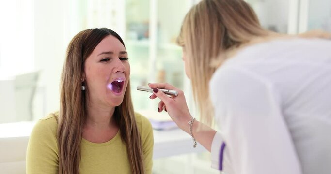 Otolaryngologist checking patient throat with flashlight in hospital