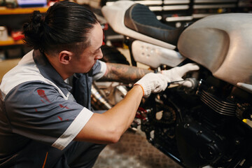 Mechanic fixing broken motorcycle of client