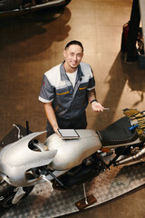 Smiling mechanic searching for cause of motorcycle breakdown