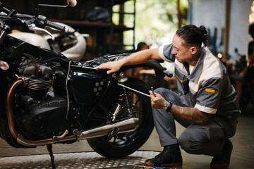 Repairman fixing motorcycle in modern garage