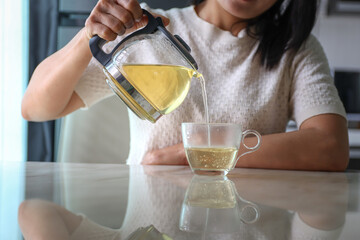 asian women pouring tea form pot
