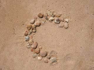 Fototapeta na wymiar Set of colorful pebbles forming a shape on beach sand background