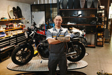Fototapeta na wymiar Portrait of happy motorcycle repair shop owner standing in his garage