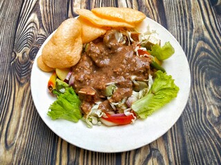 Gado Gado is an Indonesian mixed salad with peanut sauce and vegetables such as lettuce, tomatoes, cabbage, beans, potatoes, tomatoes, and red onions. Add crackers, tempeh, tofu, and rice cake