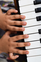 Asian cute girl playing the synthesizer or piano. Cute little kid learning how to play piano. Child's hands on the keyboard indoor.