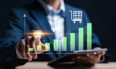 Businessman touching virtual screen of sales volume analysis graph and shopping cart for growing online sales business. Summary of the growth of online sales that continues to grow.