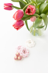Fototapeta na wymiar Pink tulips and heart-shaped pastries and candies on a white canvas close-up. Background for Valentine's Day, Easter. Gift for Women's Day, March 8th. Mockup