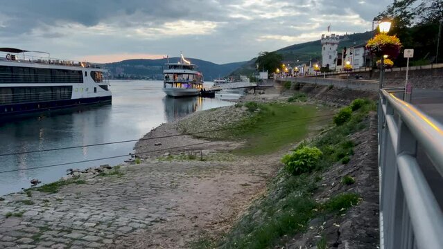 Promenade on the Rhine River in R&uuml;desheim, Germany. Large tourist ships line the shore. Evening scene. R&uuml;desheim is a town on the northern banks of the Rhine river in the wine region of Rheingau.