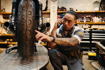 Naklejka premium Mechanic calling coworker to discuss better way to fix motorcycle breakdown