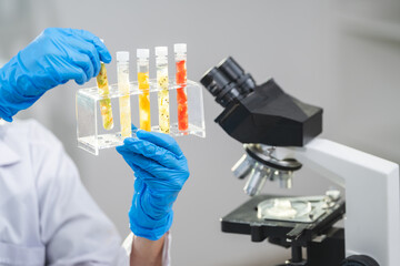 Scientist or researcher is holding a sample of fruit sample in test tube. Cosmetic laboratory. Experiment of vitamin in serum, skin care, lotion, healthy treatment, essence and medical body product.