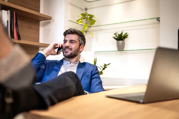 Relaxed businessman using smart phone in the office.