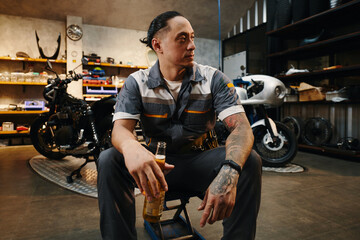 Motorcycle mechanic having bottle of beer after day of work