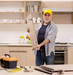 Aged contractor repairman working in the kitchen