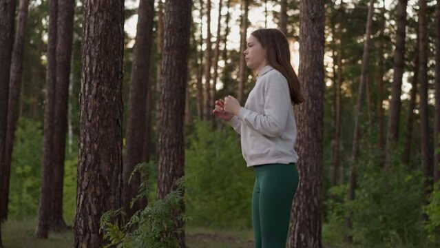 Woman jumps exercising in forest with trees