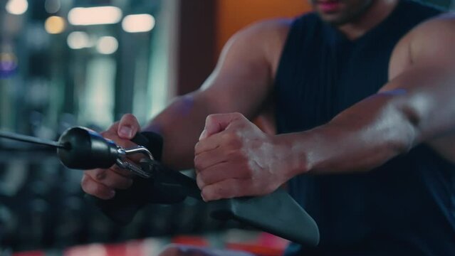 Motivated young asian sportsman having workout on rowing machine. Handsome man bodybuilder training body on modern block exercises in gym