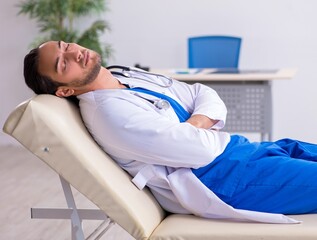 Young male doctor being tired after night shift